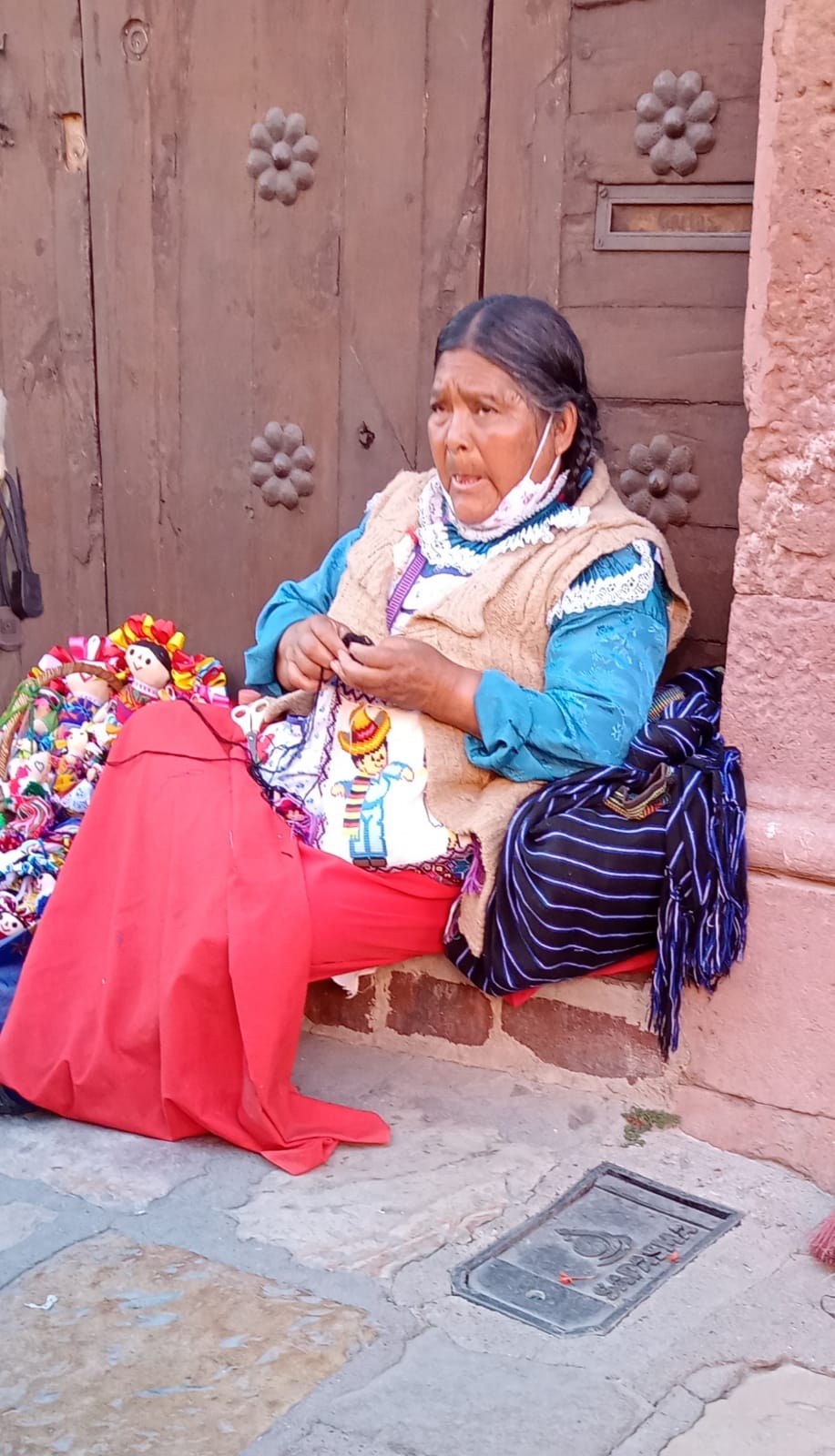 Mujer adulta mayor cose muñecas típicas de la región en San Miguel de Allende, Gto.